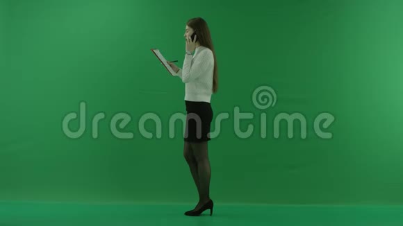 女孩站在她的左边在电话上交谈在绿色屏幕上做笔记视频的预览图