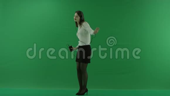 女孩站在半个转弯处看着左边戴着耳机在绿色屏幕上跳舞视频的预览图