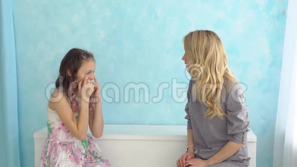 母女俩坐在一起脸贴着蓝色的墙视频的预览图