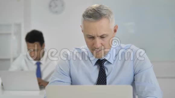 兴奋的白发商人在笔记本电脑上庆祝成功视频的预览图