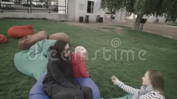妈妈和她的小女儿在户外小女孩去找她的妹妹她拥抱和亲吻她视频的预览图