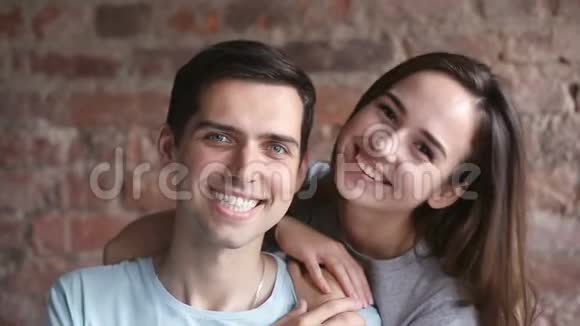 可爱的年轻夫妇看着摄像机微笑着拥抱在室内视频的预览图
