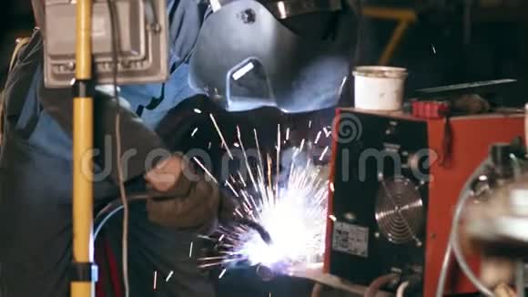 防护辉光男工在机械机库焊接两个金属件视频的预览图