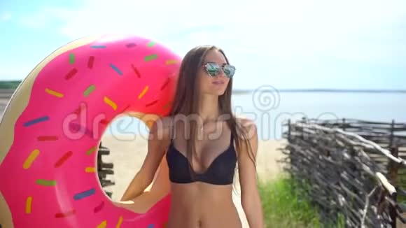 在阳光明媚的日子里比基尼女孩带着洒满甜甜圈在游泳池里漂浮派对酒店海滩度假度假旅行视频的预览图