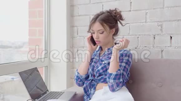 快乐的女人在家里放松打电话工作笔记本电脑视频的预览图