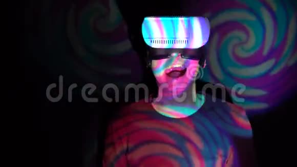 在明亮的聚光灯背景下戴着虚拟现实耳机的人在嘲笑摄像机视频的预览图