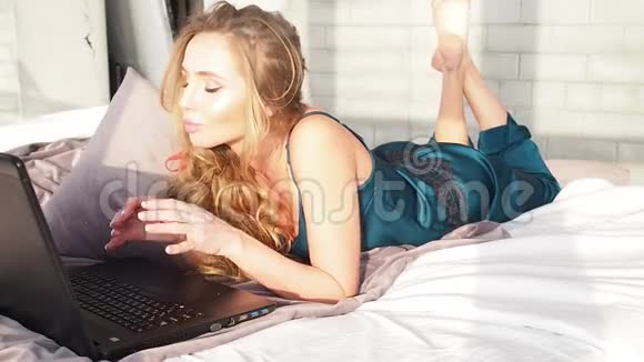 金发女郎在卧室里用笔记本电脑对着相机微笑视频的预览图