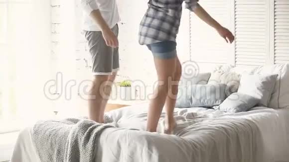 在舒适的卧室里年轻夫妇站在舒适的床上跳舞视频的预览图