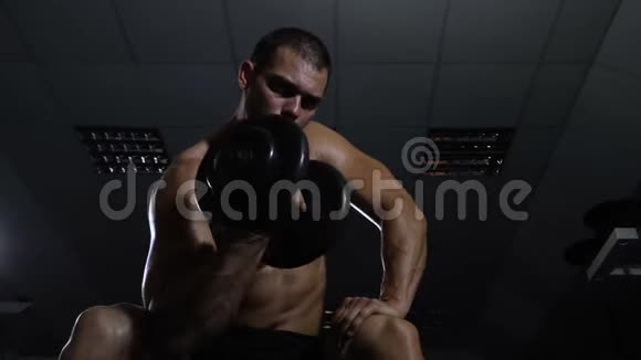 男人在健身房训练运动员用哑铃训练他的二头肌视频的预览图