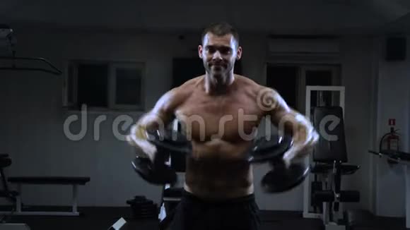 肌肉男在健身房用哑铃训练家伙用三角肌视频的预览图