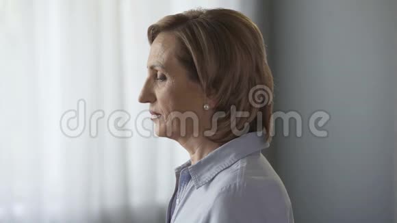 悲伤的老年女性站在窗边男性扶着她的肩膀视频的预览图