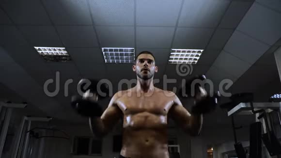 肌肉男在健身房用哑铃训练家伙用三角肌视频的预览图