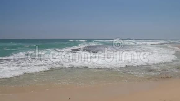 海浪在蔚蓝的天空下缓缓地在热带海滩上翻滚视频的预览图
