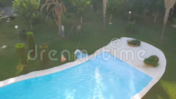在阳光明媚的夏日豪华的室外游泳池配有蓝色的水和阳光反射顶部视图视频的预览图