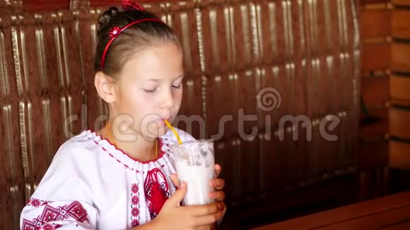 快乐的微笑少女孩子在咖啡馆喝奶昔她穿着乌克兰民族服装刺绣视频的预览图