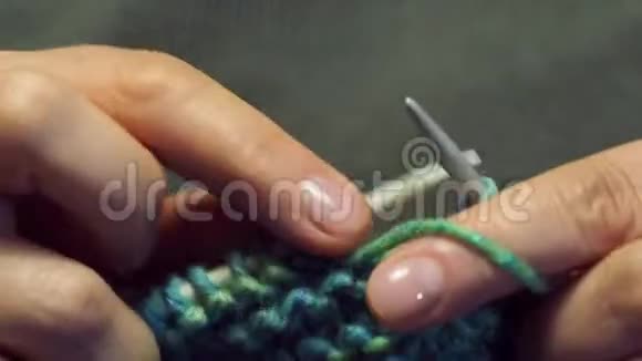 女性的手指在温暖的灯光下编织一条围巾视频的预览图