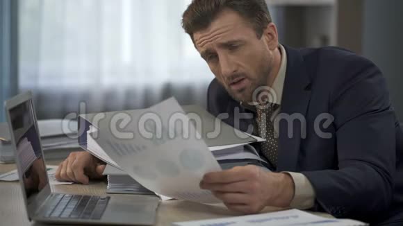 一个人被办公室里的文书工作包围着看图表头掉在文件夹上视频的预览图