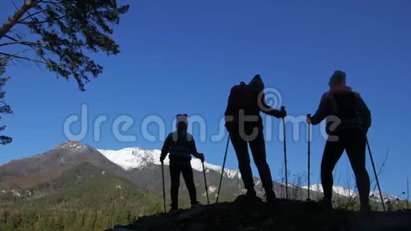 女人在山上行走在大自然中剪影女孩和孩子使用跋涉棒和北欧杆视频的预览图