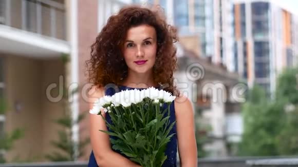 一个美丽的卷发女孩带着花的肖像视频的预览图