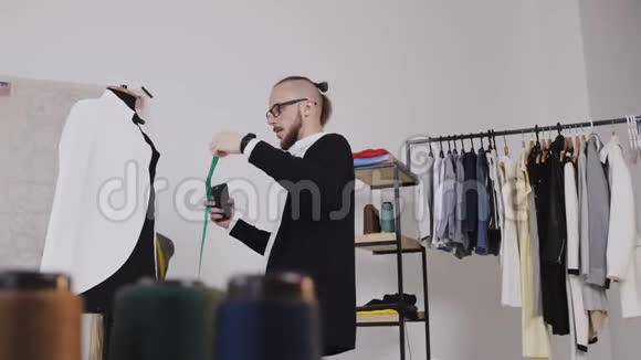 一位有创意的裁缝或时装设计师在他的工作室里用一件白色夹克来缝制衣服视频的预览图