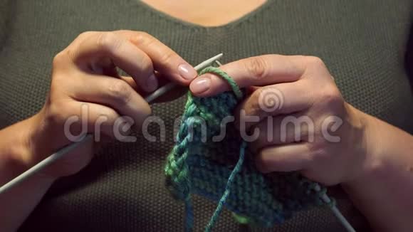 女人的手在温暖的灯光下编织一条围巾视频的预览图