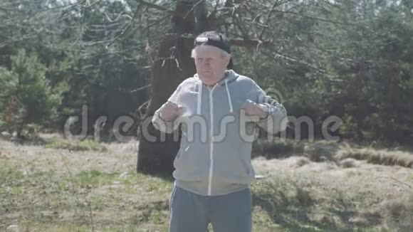 快乐的老人在早期的森林里伸展身体4K视频的预览图