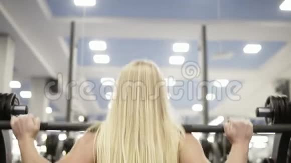 年轻漂亮的金发女郎和杠铃一起蹲做运动举重健康的生活方式观念视频的预览图