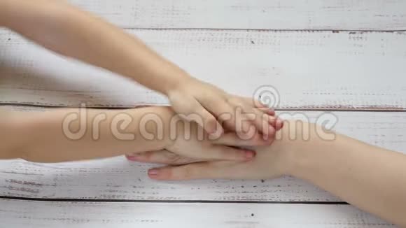 孩子把手放在母亲的手上特写镜头手拉手放在木桌的背景上慢慢地视频的预览图