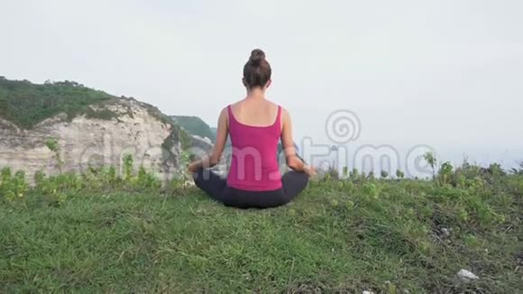 年轻女子在悬崖上练习瑜伽锻炼镇静和谐视频的预览图