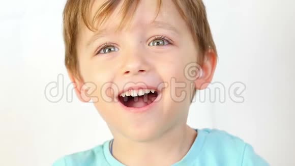 一个小孩的特写镜头高兴地微笑着看着摄像机双手抱着头闭上耳朵视频的预览图