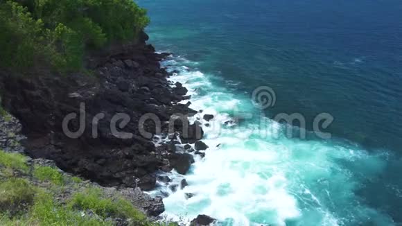 暴风雨时海浪溅落在岩石峭壁上蓝色的海浪随着泡沫和浪花破碎到石质海岸绿松石视频的预览图