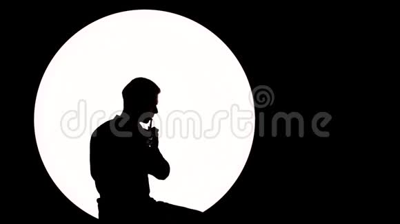 音乐人的剪影一个年轻人吹长笛而坐在白色的圆圈背景上作为满月视频的预览图