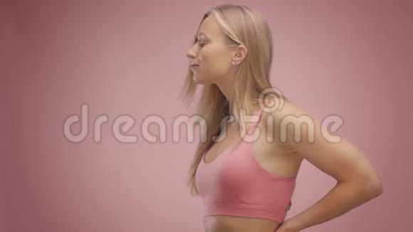 粉红背景工作室里的金发模特头发吹在空中视频的预览图