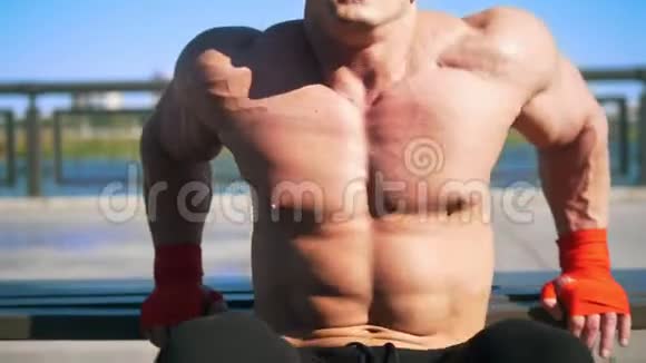 强壮的肌肉男子有力量训练户外推UPS从运动板凳视频的预览图