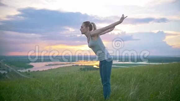 夏季日落时年轻的运动女子在山上表演杂技跳跃视频的预览图