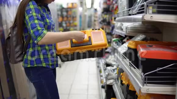 一个年轻的女人在商店里选择一个塑料工具箱视频的预览图