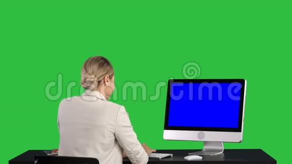 女人在办公室里看着显示器绿色屏幕Chroma键蓝色屏幕模拟显示视频的预览图