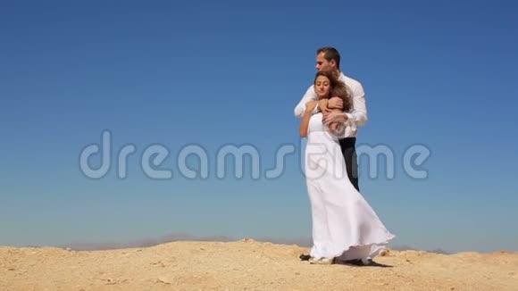 可爱快乐的一对新婚夫妇温柔地拥抱在沙滩上的蓝天在埃及视频的预览图