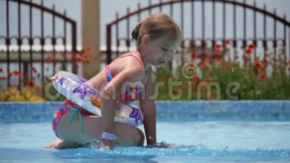 快乐的小女孩在炎热的夏天在户外游泳池里玩五颜六色的充气戒指孩子们学游泳视频的预览图