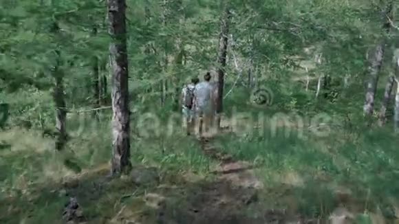 后景背着背包的夫妇在森林里走一条小路视频的预览图