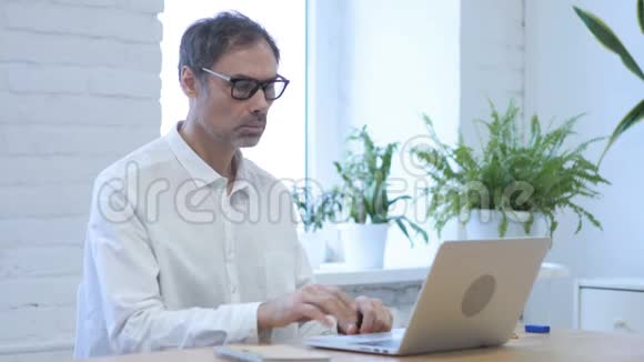 在笔记本电脑上思考和工作的中年男人视频的预览图
