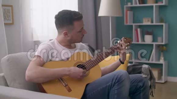 手持的年轻人在他舒适的客厅里弹吉他视频的预览图