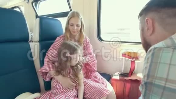 年轻的白种人一家人一起旅行母亲父亲和小女儿在靠近窗户的火车上交谈视频的预览图