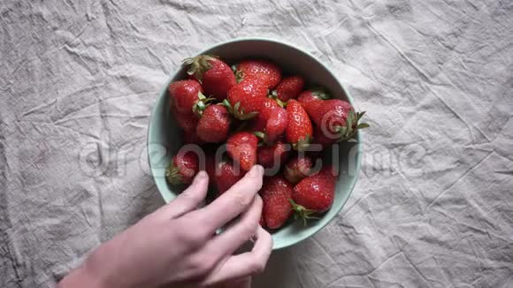从碗里取草莓的不同手的近镜头视频的预览图