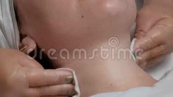 戴透明手套的美容师用白色餐巾纸擦擦颈部皮肤一部分面部的特写视频的预览图