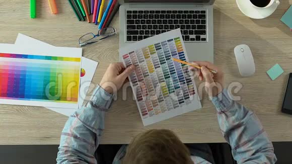 设计师选择调色板上的颜色并在办公室的笔记本电脑上工作顶部视图视频的预览图