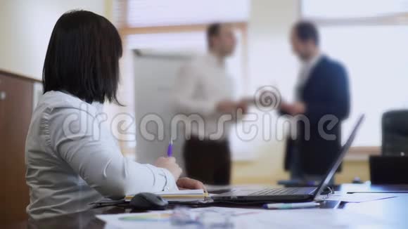 女人坐在餐桌前开会听同事们为项目争论视频的预览图