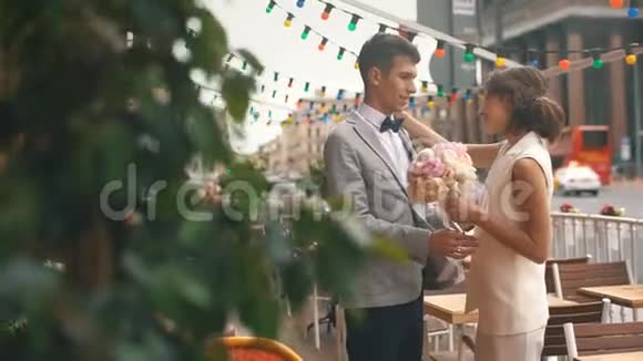 新婚夫妇拥抱在餐厅的夏季露台上视频的预览图