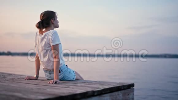 年轻的苗条女士正在湖边享受夏日日落放松身心视频的预览图