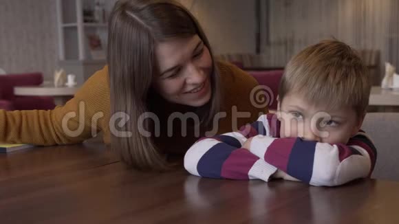 妈妈安慰小儿子她坐在咖啡馆里的一张桌子儿子视频的预览图
